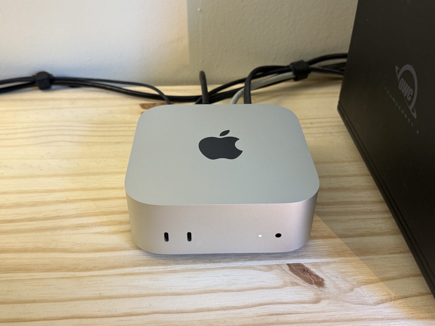 Mac mini M4 sitting on a desk with various cables plugged into the back