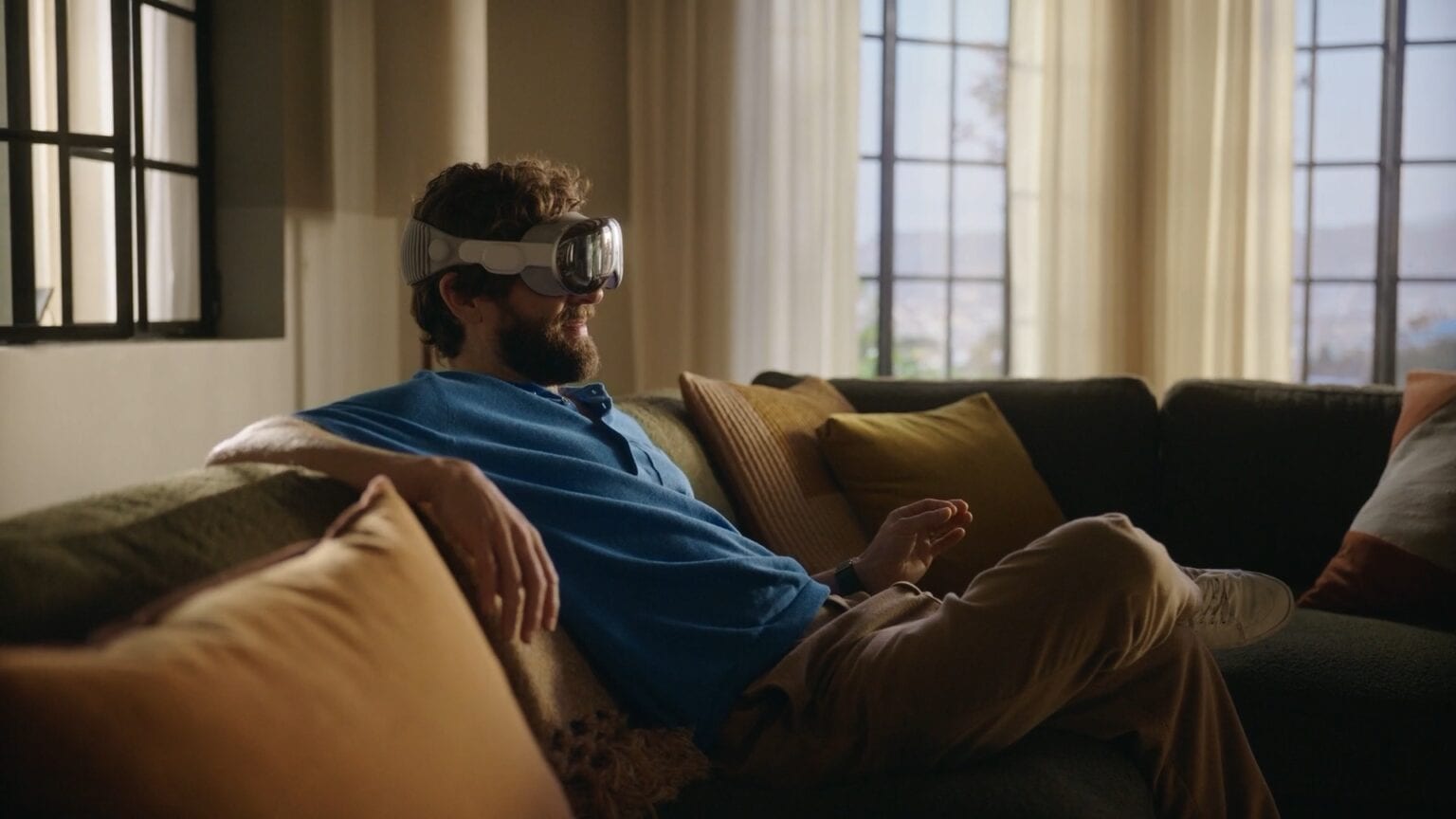 Man sitting on a couch with a Vision Pro making a pinch gesture with his fingers