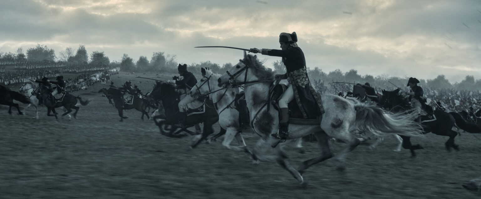 Napoleon (played by Joaquin Phoenix) leads the charge on a grim battlefield.