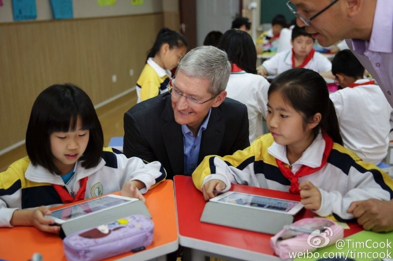 Photo of Apple CEO Tim Cook talking with Chinese children to illustrate an Apple history article about the deal that brought the iPhone to China Mobile, the world's largest carrier.